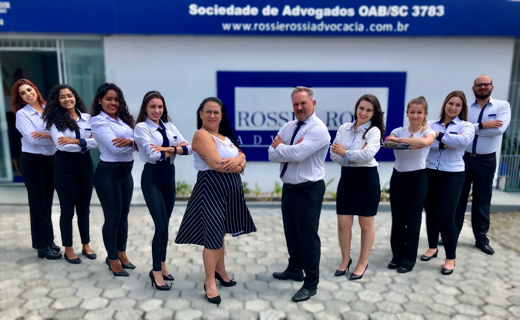 A equipe da Rossi e Rossi Advocacia na frente da sede, sob a faixa Sociedade de Advogados OAB/SC 3783